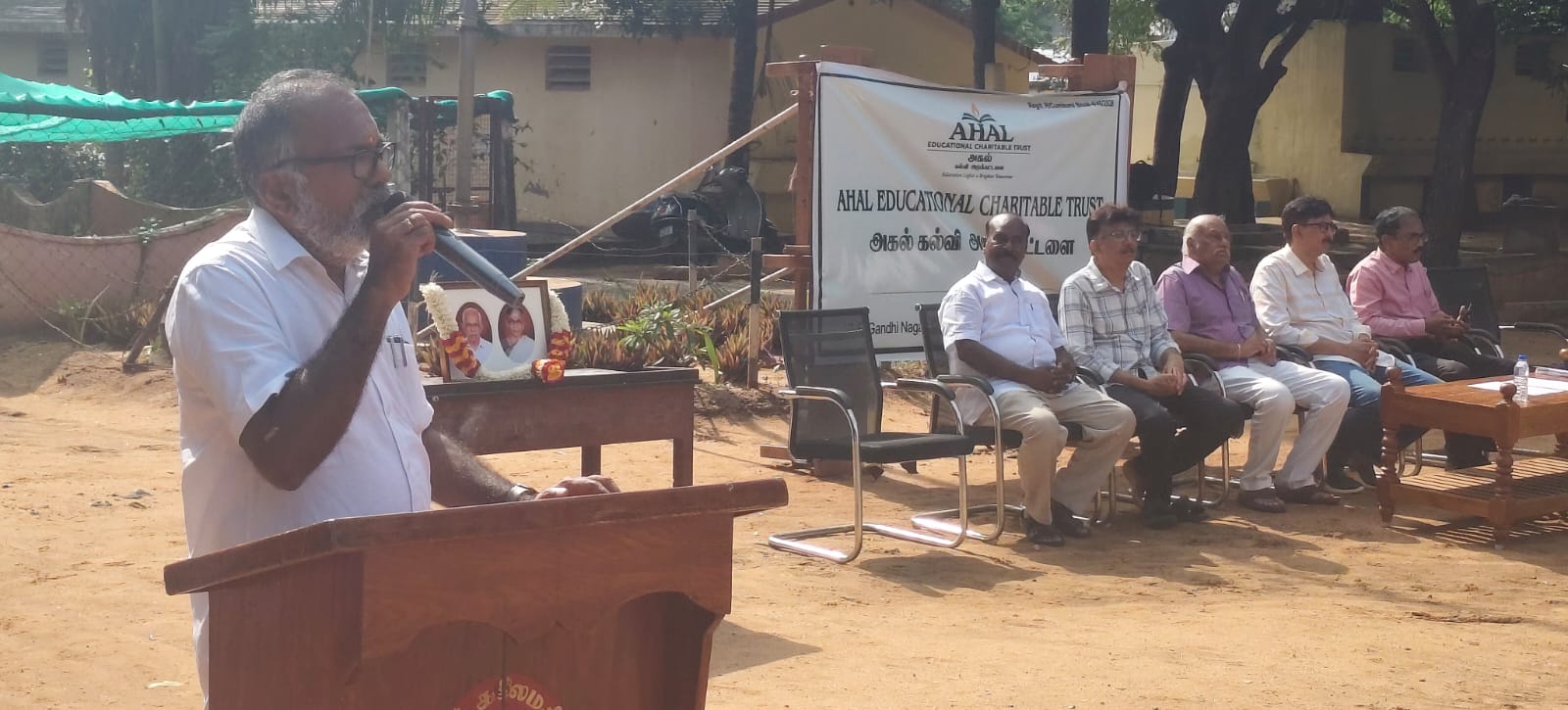 A speaker at the podium, with trustees seated beside the AHAL banner